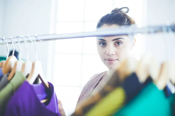 Smuk ung stylist nær rack med bøjler - Stock-foto