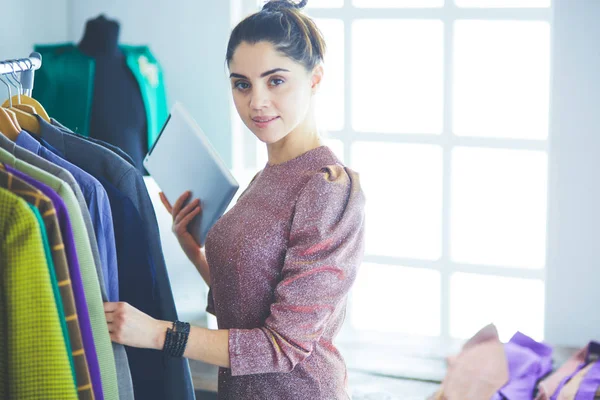 Mooie jonge stylist bij rek met hangers — Stockfoto