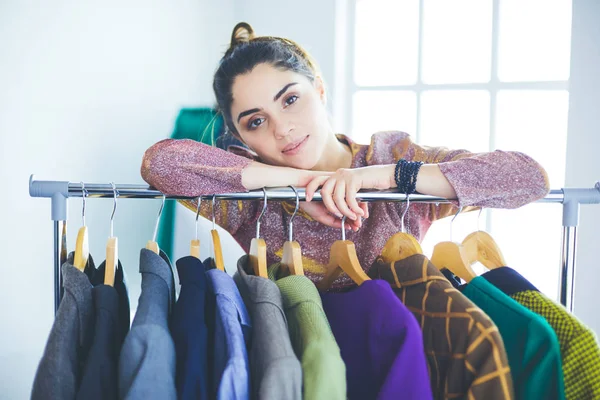 Mooie jonge stylist bij rek met hangers — Stockfoto