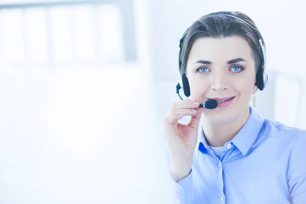 Ernstige mooie jonge vrouw die werkt als support telefoon operator met headset in het kantoor — Stockfoto