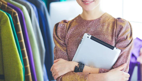 Mooie jonge stylist bij rek met hangers — Stockfoto