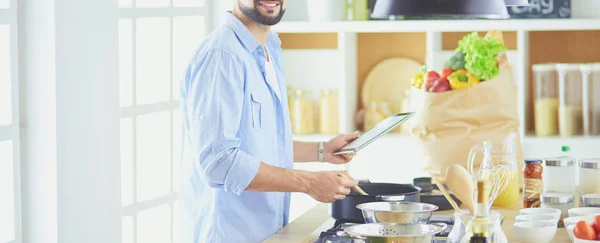 Man volgens recept op digitale tablet en lekker en gezond koken in de keuken thuis — Stockfoto