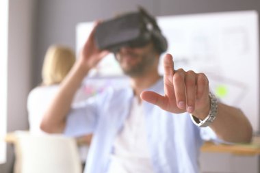 Genç erkek yazılım programcısı ofiste üç boyutlu sanal gerçeklik gözlükleriyle yeni bir uygulama test ediyor..