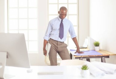 Ofiste bilgisayar ve planlarla çalışan Afrikalı Amerikalı bir mimar.