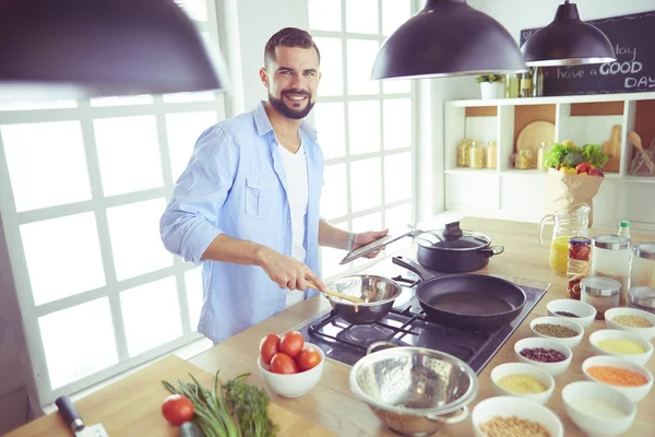 Man volgens recept op digitale tablet en lekker en gezond koken in de keuken thuis — Stockfoto