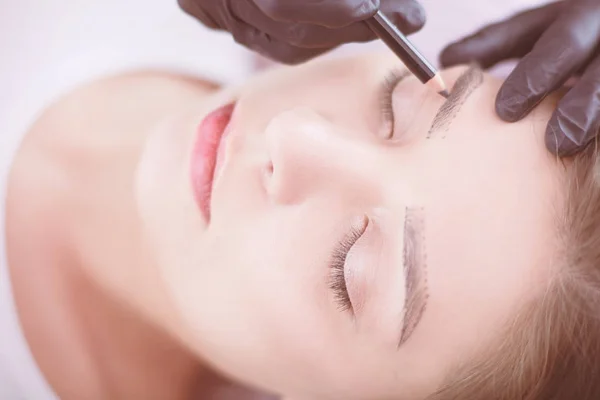 Cosmetólogo aplicando maquillaje permanente en las cejas — Foto de Stock