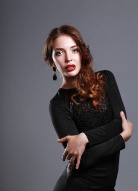 Gri arka plan üzerinde siyah elbiseli mutlu genç kadın portresi