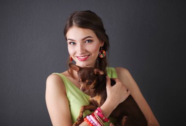 Gri arka planda köpeği olan çekici bir kadın.