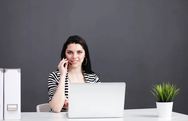 Retrato de mulher de negócios bonita trabalhando em sua mesa com fone de ouvido e laptop — Fotografia de Stock