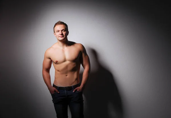 Retrato de un hombre musculoso guapo de pie sobre fondo gris —  Fotos de Stock