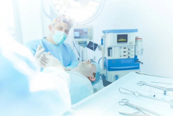 Homem cirurgião no trabalho na sala de cirurgia — Fotografia de Stock