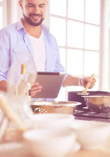 Dijital tablet ve yemek pişirme tarifine uyan bir adam evdeki mutfakta lezzetli ve sağlıklı yemekler pişiriyor. — Stok fotoğraf