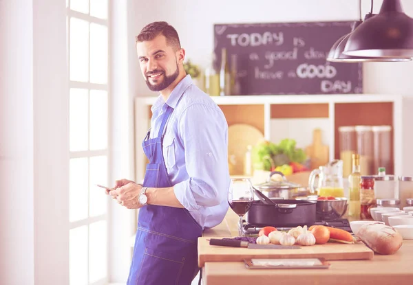 Muž držící papírovou tašku plnou potravin na pozadí kuchyně. Nákupní a zdravé potraviny koncept — Stock fotografie