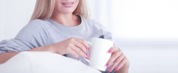 Portrét mladé ženy sedí na pohovce s šálkem kávy — Stock fotografie