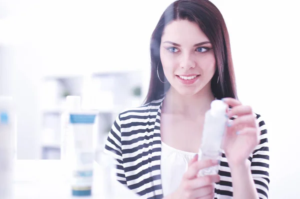 Beautiful young woman in shop holding a bottle — Stock Photo, Image