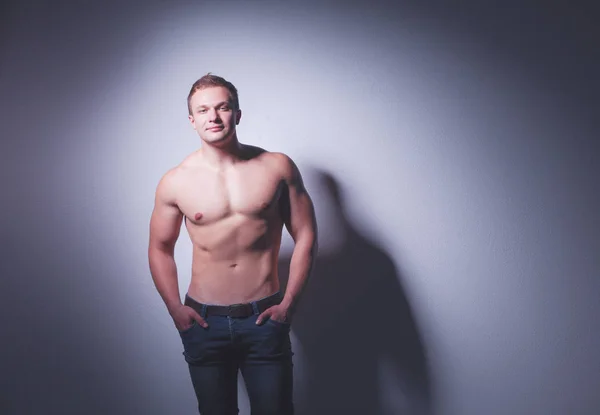 Портрет красивого мускулистого человека, стоящего на сером фоне — стоковое фото