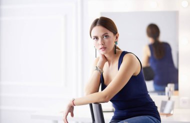 Beyaz arka planda izole edilmiş bir sandalyede oturan genç kadın.