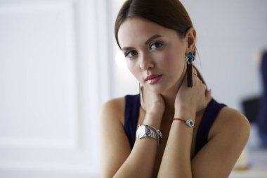 Beyaz arka planda izole edilmiş bir sandalyede oturan genç kadın.