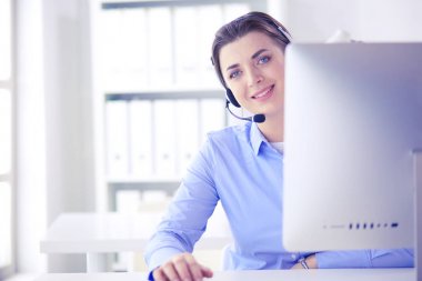Ofisinde kulaklık takmış, telefon operatörü olarak çalışan ciddi ve güzel bir genç kadın.