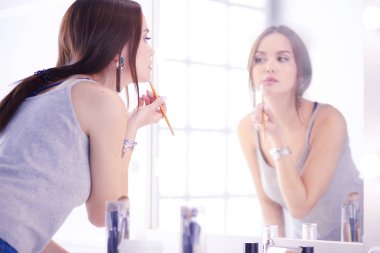 Genç kadın ruj bir ayna önünde uygulama