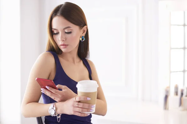 Kafede kahve içip cep telefonuyla konuşan genç bir kadın. — Stok fotoğraf