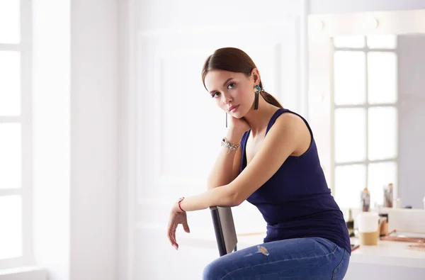 Jonge vrouw zitten op een stoel geïsoleerd over witte achtergrond — Stockfoto