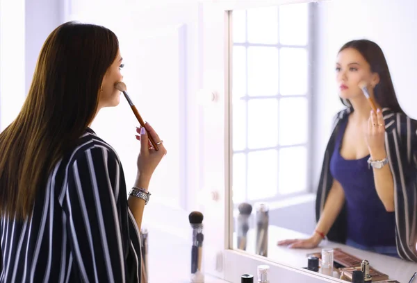 美容女性メイクを適用します。美しい少女、鏡で見ていると大きなブラシで化粧品を適用します。 — ストック写真