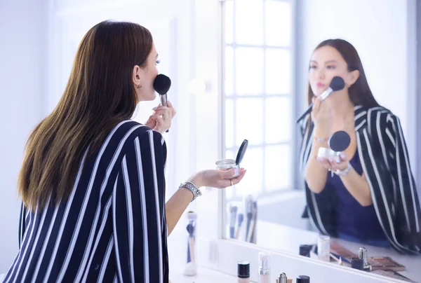 Piękna dziewczyna patrząc w lustro i stosując kosmetyk z dużą szczotką — Zdjęcie stockowe