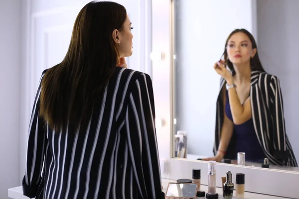 Reflet de jeune belle femme appliquant son maquillage, regardant dans un miroir — Photo