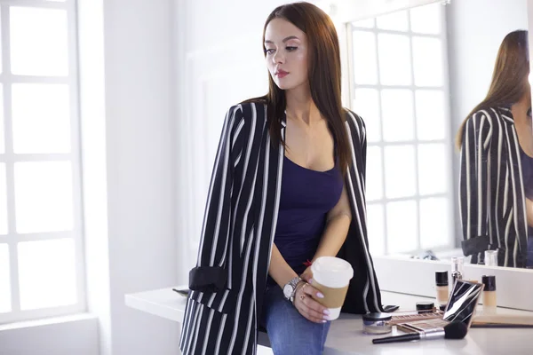 Şık kadın cappuccino fincan içme sanatçı makyaj ve modern iç ziyaretçi bekliyor — Stok fotoğraf