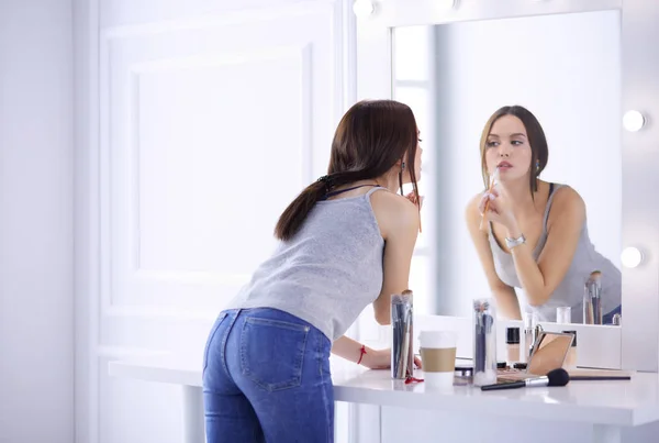 Junge Frau trägt Lippenstift vor dem Spiegel auf — Stockfoto