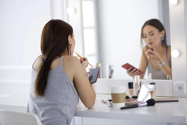 Mujer joven que aplica lápiz labial delante de un espejo —  Fotos de Stock