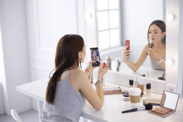 Blogger de belleza filmando tutorial de maquillaje con teléfono inteligente frente al espejo — Foto de Stock