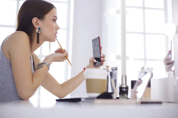 Weibliche junge schöne Mädchen mit lockigem Haar und Make-up. Schöne Frau macht Selbstporträt per Telefon — Stockfoto