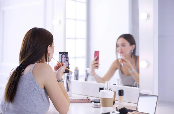 Weibliche junge schöne Mädchen mit lockigem Haar und Make-up. Schöne Frau macht Selbstporträt per Telefon — Stockfoto