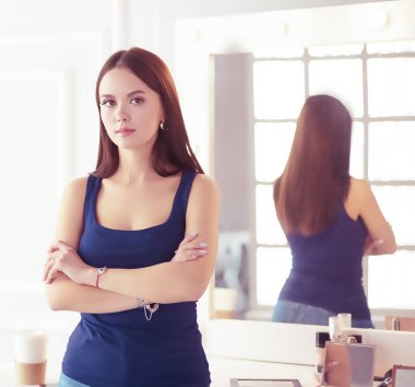 Salonda elleri katlanmış duran kadın