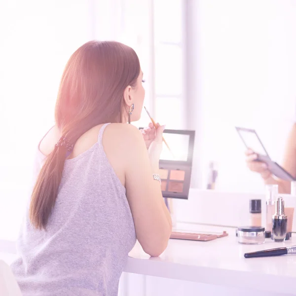 Brunette vrouw solliciteren make-up voor een avond date voor een spiegel — Stockfoto