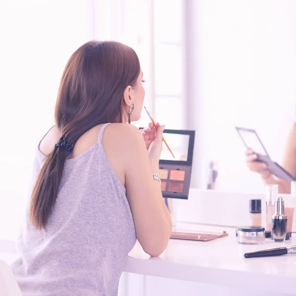 Mujer morena aplicando maquillaje para una cita nocturna frente a un espejo —  Fotos de Stock