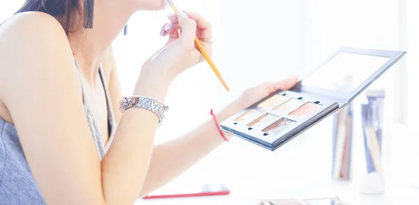 Mujer morena aplicando maquillaje para una cita nocturna frente a un espejo —  Fotos de Stock