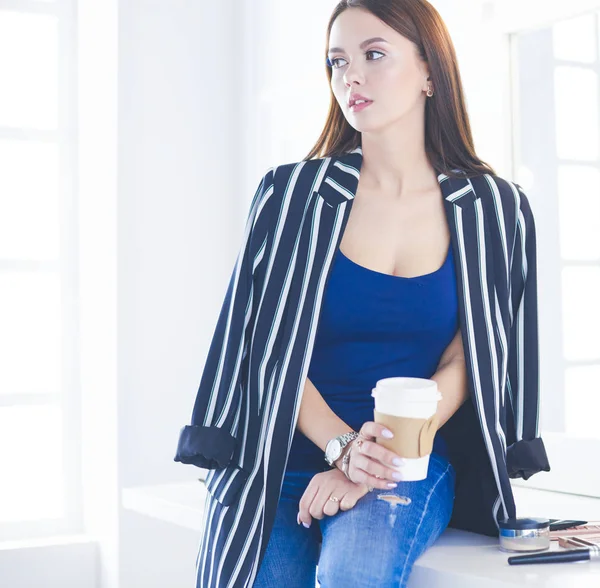 Elegante mujer conforman artista bebiendo taza de capuchino y esperando a los visitantes en el interior moderno — Foto de Stock