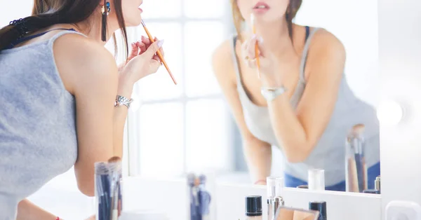 Junge Frau trägt Lippenstift vor dem Spiegel auf — Stockfoto