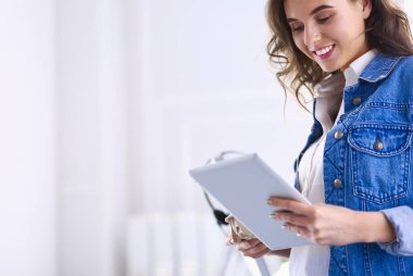 Gülümseyen kadın kahve içiyor ve kafede tablet kullanıyor.