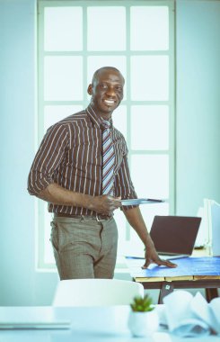 Ofiste bilgisayar ve planlarla çalışan Afrikalı Amerikalı bir mimar.