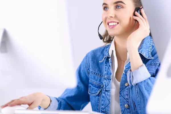 快乐迷人的年轻女性坐着，在办公室用耳机与笔记本电脑一起工作 — 图库照片