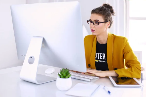 Joven empresaria confiada trabajando en el escritorio de la oficina y escribiendo con una computadora portátil — Foto de Stock