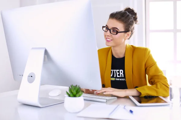 Joven empresaria confiada trabajando en el escritorio de la oficina y escribiendo con una computadora portátil — Foto de Stock