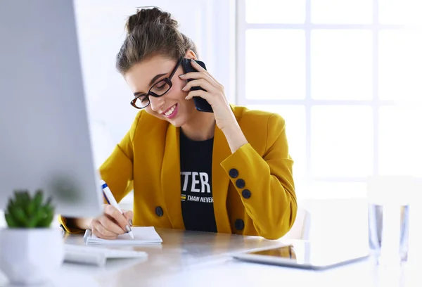 Donna d'affari seduta in ufficio con computer portatile al telefono — Foto Stock