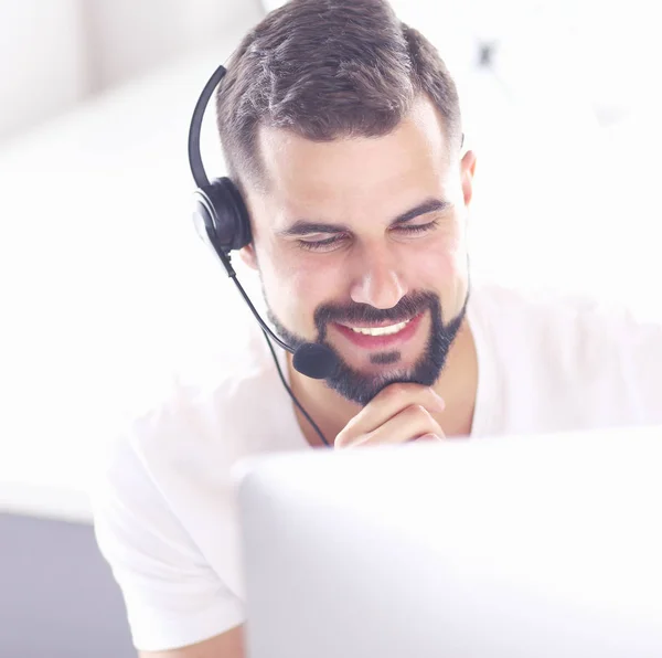 Retrato de un joven con un auricular frente a una computadora portátil — Foto de Stock