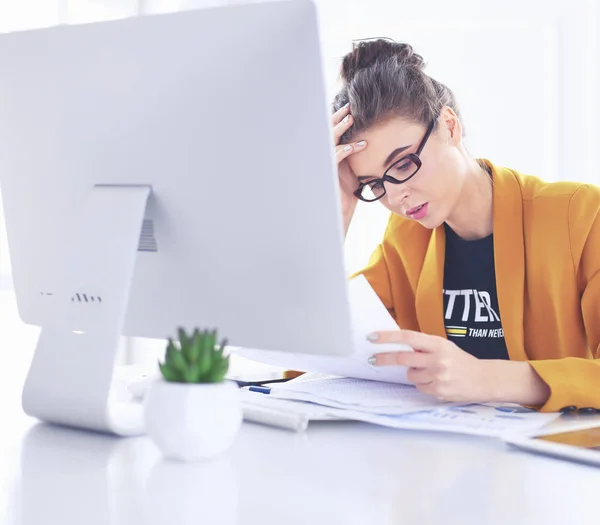 Atrakcyjna kobieta siedząca przy biurku w biurze, współpracując z komputerem przenośnym, trzymając dokument — Zdjęcie stockowe