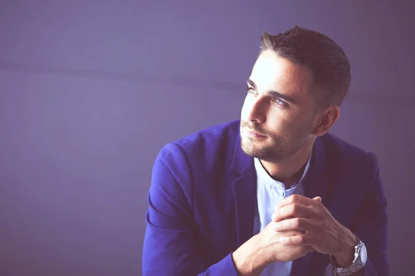 Jonge zakenman zit geïsoleerd op grijze achtergrond. — Stockfoto